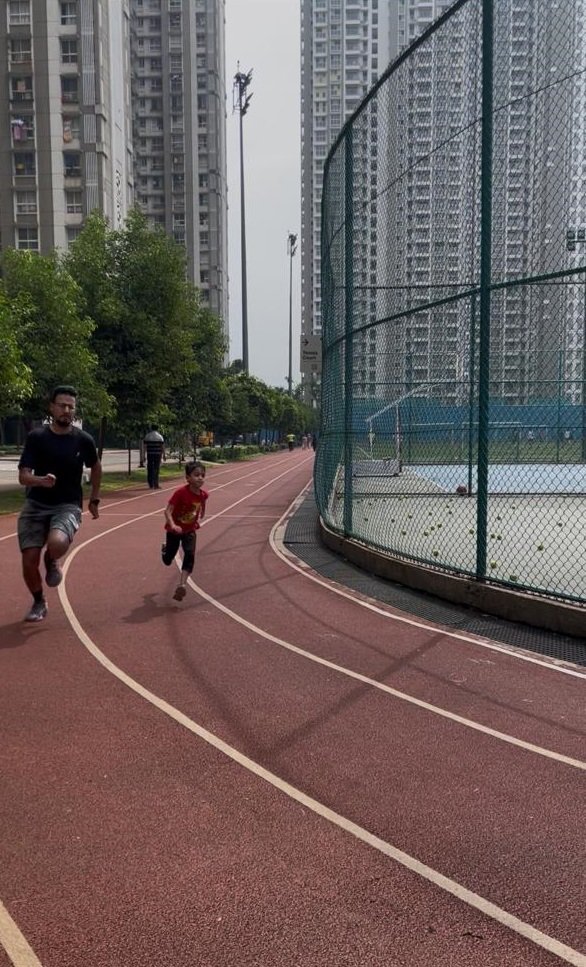 A 7-year-old child and a 27-year-old marathon trainee sprinting side-by-side during a slow-motion sprint session at VHR Sports Academy