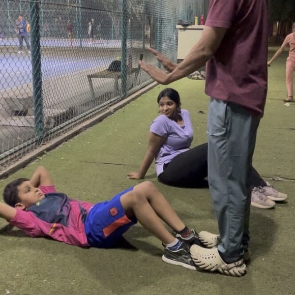 Coach guiding a young athlete through a core exercise at VHR Sports